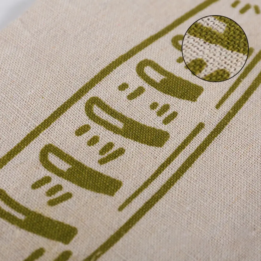 Close-up of the bag cloth: the olive loaf motif printed on the woven fibre, with an inset magnifying the weave